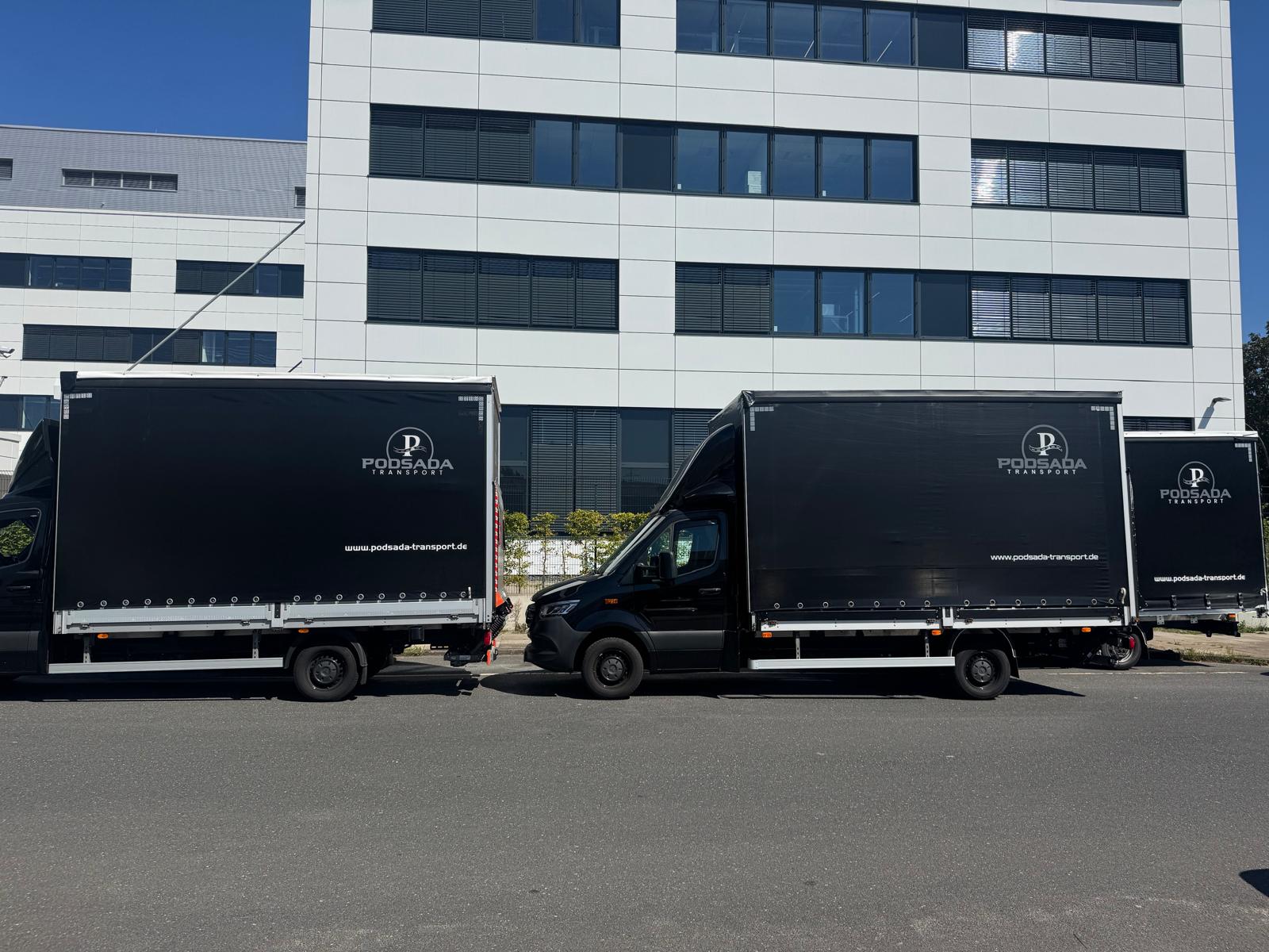 Flota ciężarówek Podsada Transport zaparkowana przed nowoczesnym biurowcem